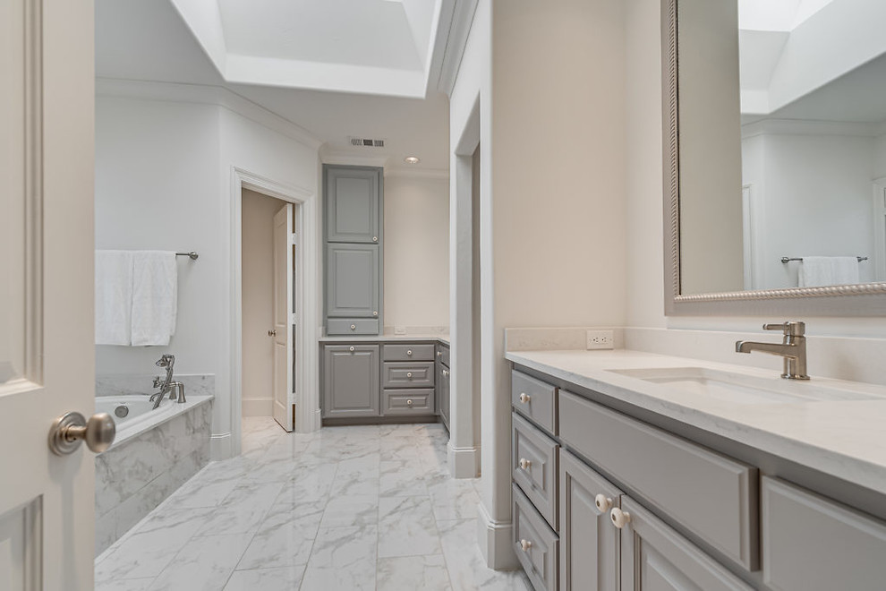 Expansive modern master bathroom in Dallas with grey cabinets, a drop-in tub, a corner shower, white walls, multi-coloured floor, a hinged shower door, raised-panel cabinets, a two-piece toilet, white tile, porcelain tile, porcelain floors, an undermount sink, quartzite benchtops and white benchtops.