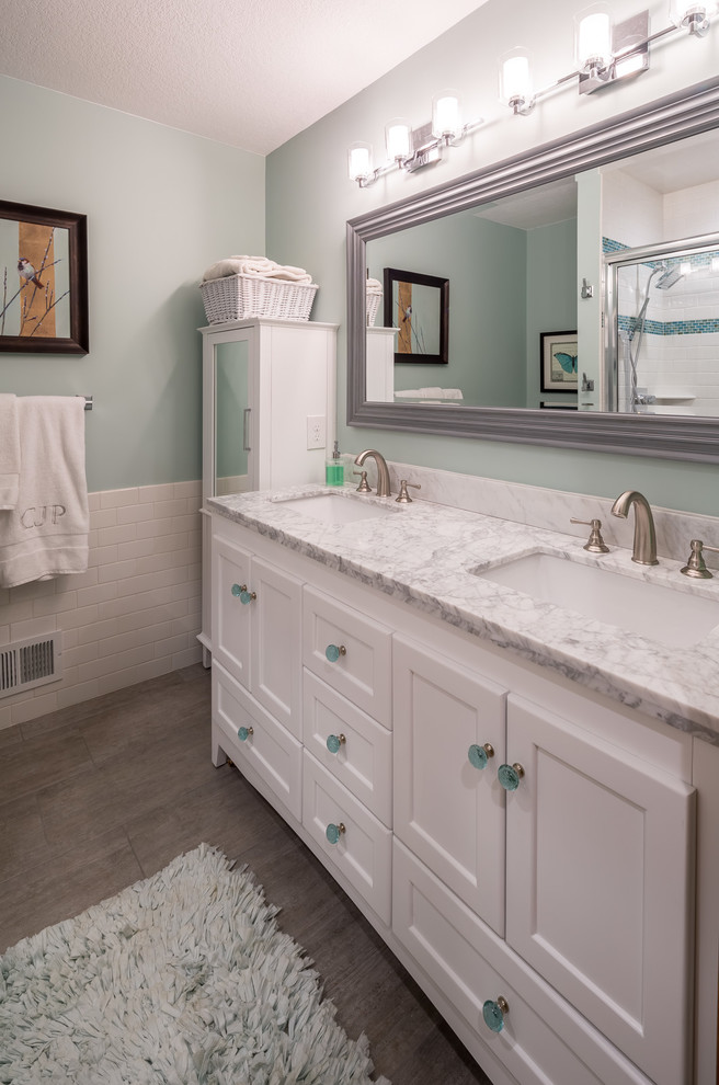 This is an example of a mid-sized transitional master bathroom in Minneapolis with furniture-like cabinets, white cabinets, a freestanding tub, gray tile, ceramic tile, green walls, ceramic floors, an integrated sink, an alcove shower, a one-piece toilet and marble benchtops.