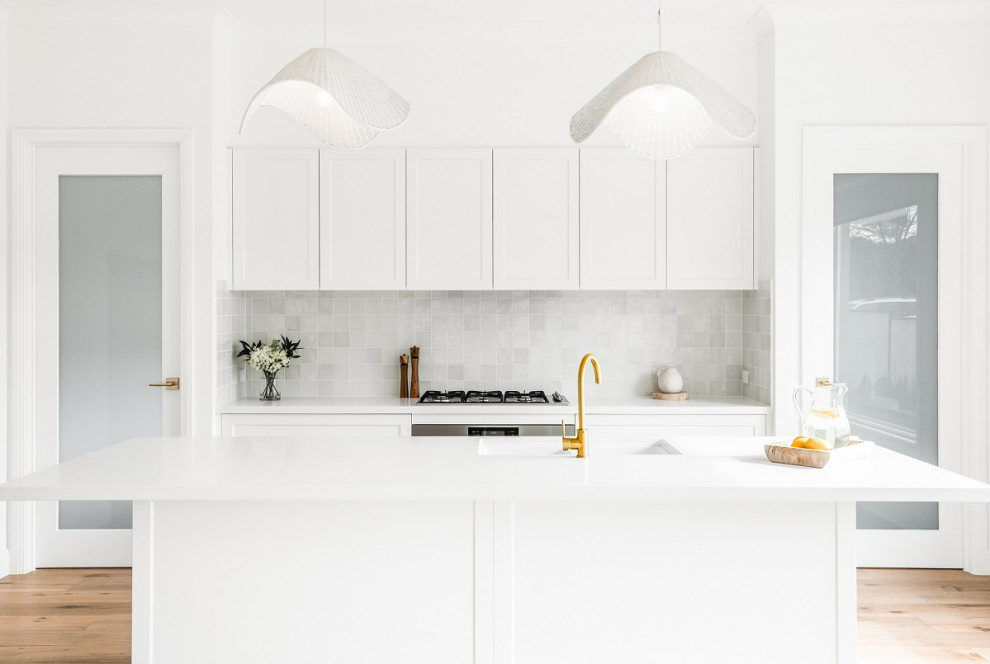 Inspiration for a contemporary galley kitchen remodel in Sydney with white cabinets, quartz countertops, stone tile backsplash, stainless steel appliances, an island and white countertops