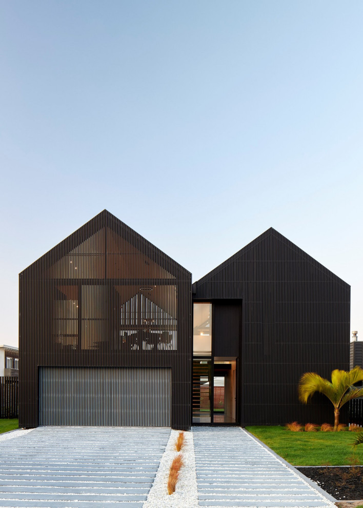 Exemple d'une façade de maison noire scandinave en bois et bardage à clin de taille moyenne et à un étage avec un toit à deux pans, un toit en métal et un toit noir.
