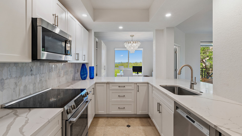 This is an example of a small classic grey and white u-shaped kitchen in Tampa with a submerged sink, shaker cabinets, white cabinets, engineered stone countertops, white splashback, ceramic splashback, stainless steel appliances, porcelain flooring, beige floors and white worktops.
