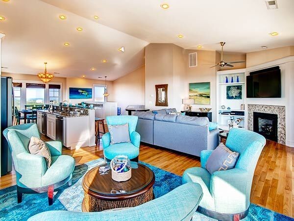 This is an example of a mid-sized beach style formal open concept living room in Other with beige walls, medium hardwood floors, a corner fireplace, a tile fireplace surround and a wall-mounted tv.