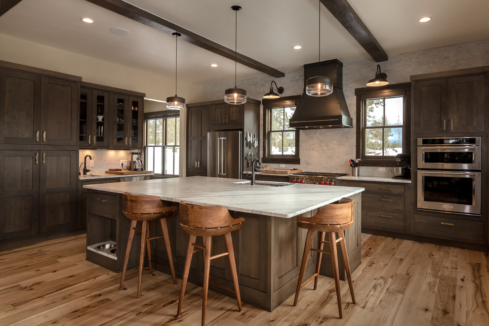 Inspiration for a large country l-shaped open plan kitchen in Denver with an undermount sink, shaker cabinets, dark wood cabinets, stainless steel appliances, light hardwood floors, with island, white benchtop, quartz benchtops, beige floor, beige splashback and subway tile splashback.