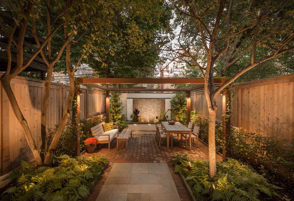 This is an example of a small contemporary backyard patio in Philadelphia with a water feature, brick pavers and a pergola.