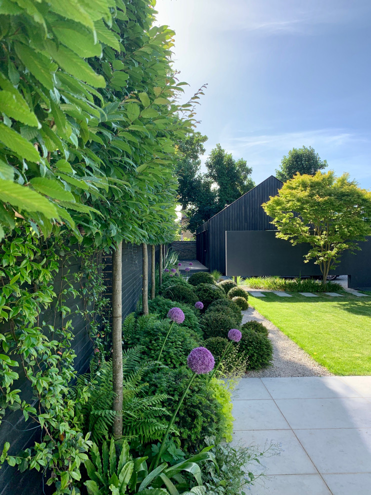 Esempio di un giardino minimal esposto in pieno sole di medie dimensioni e dietro casa in estate con pavimentazioni in pietra naturale e recinzione in legno