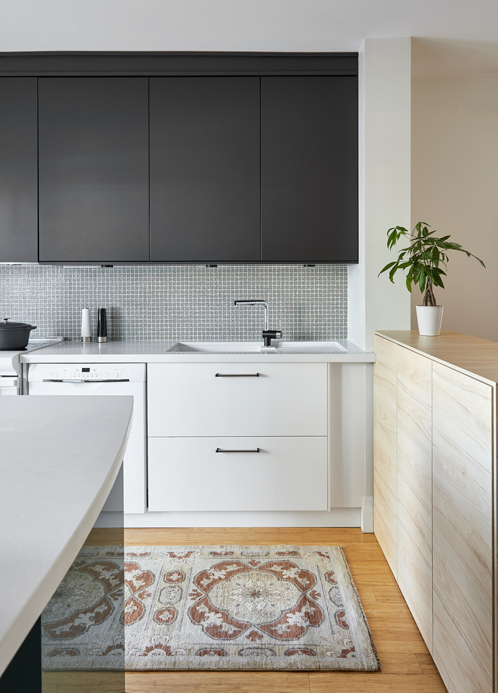 Inspiration for a mid-sized scandinavian l-shaped kitchen in Raleigh with an undermount sink, flat-panel cabinets, black cabinets, quartz benchtops, white appliances, bamboo floors, a peninsula, white benchtop and yellow floor.