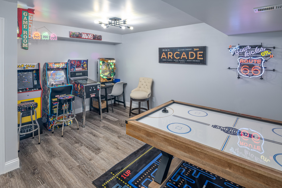 This is an example of a medium sized eclectic enclosed games room in Cincinnati with a game room, grey walls, vinyl flooring, a wall mounted tv and brown floors.