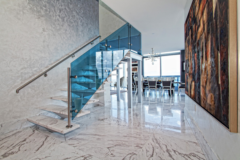 Mid-sized contemporary marble floating staircase in Miami with open risers and glass railing.