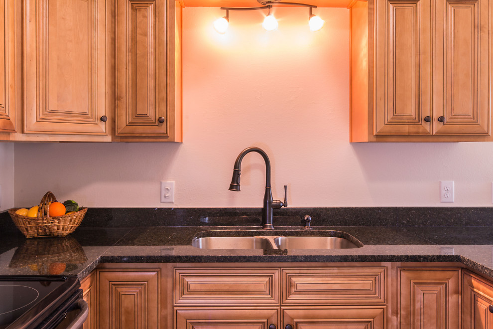 Eat-in kitchen - small u-shaped eat-in kitchen idea with an undermount sink, raised-panel cabinets, medium tone wood cabinets, granite countertops, stainless steel appliances and a peninsula