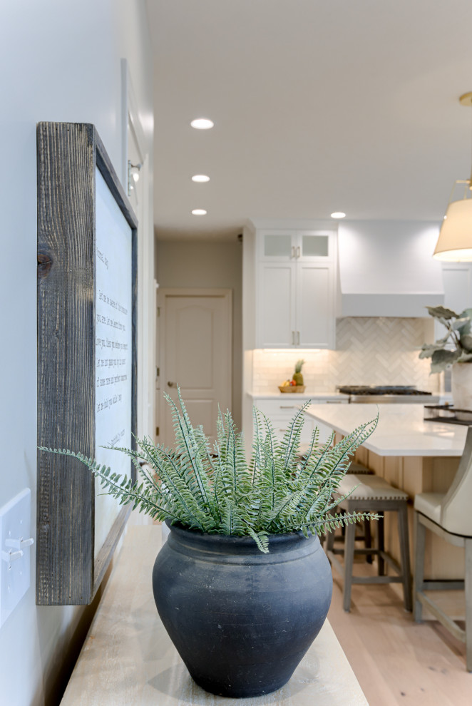 Transitional light wood floor and beige floor open concept kitchen photo with an undermount sink, white cabinets, quartzite countertops, multicolored backsplash, stainless steel appliances and an island