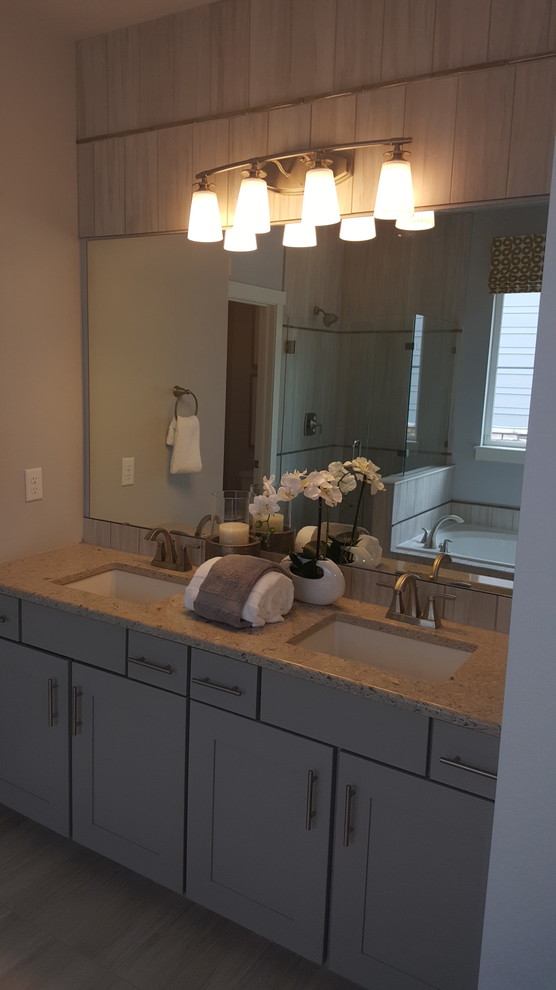 Photo of a mid-sized traditional master bathroom in Denver with recessed-panel cabinets, grey cabinets, a drop-in tub, a corner shower, gray tile, ceramic tile, grey walls, ceramic floors, an undermount sink and granite benchtops.
