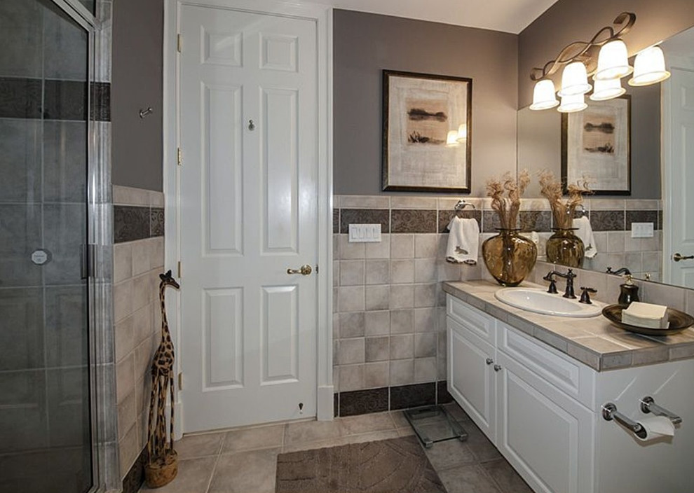 This is an example of a large transitional bathroom in DC Metro with a drop-in sink, raised-panel cabinets, white cabinets, tile benchtops, a two-piece toilet, gray tile, ceramic tile, grey walls, ceramic floors, with a sauna, an alcove shower, white floor and a hinged shower door.