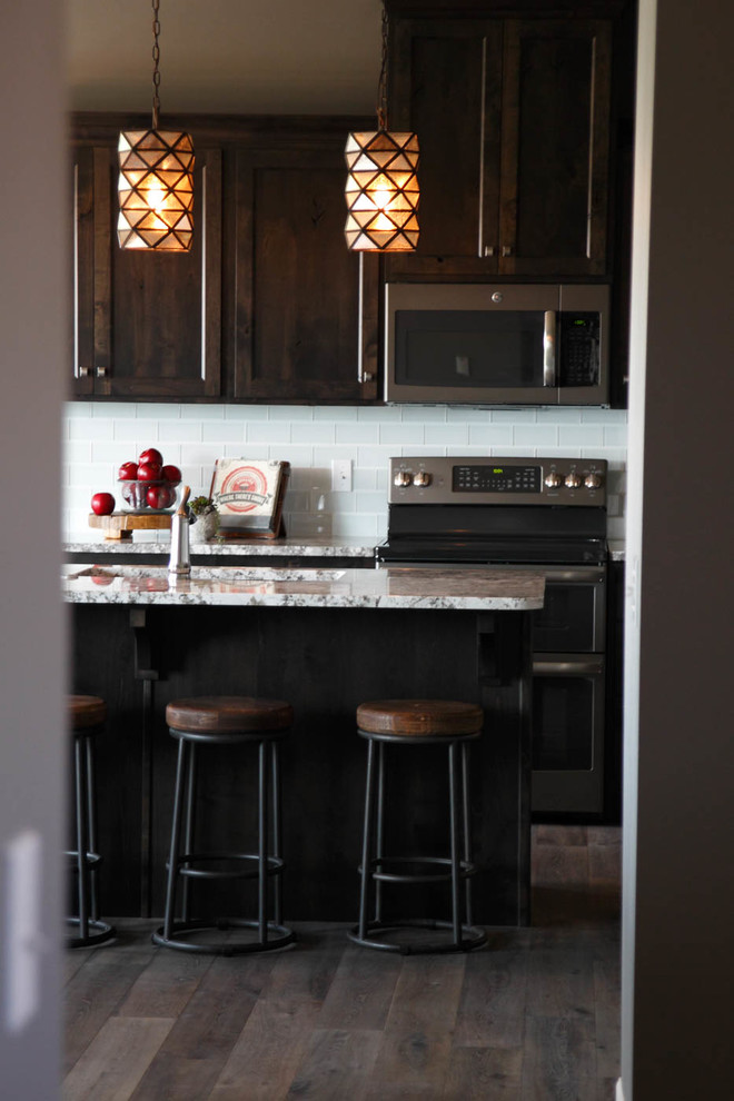 Enclosed kitchen - large transitional l-shaped medium tone wood floor enclosed kitchen idea with dark wood cabinets, granite countertops, white backsplash, glass tile backsplash, stainless steel appliances, an island and shaker cabinets