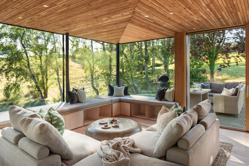 Inspiration for an expansive country sunroom in Devon with medium hardwood floors, a hanging fireplace, a concrete fireplace surround and brown floor.