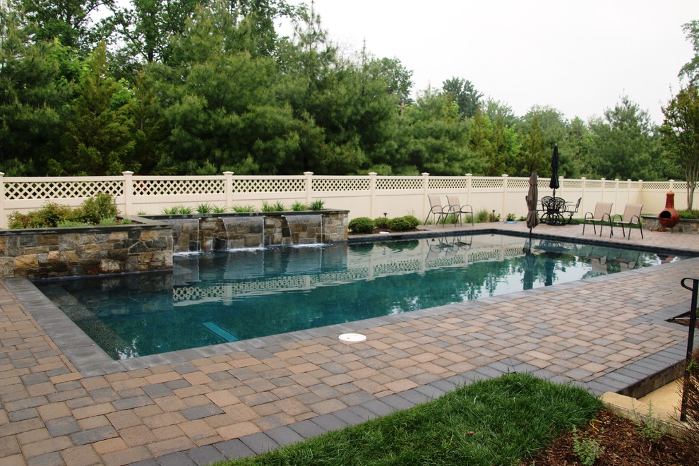 Design ideas for a mid-sized traditional backyard rectangular pool in Baltimore with a water feature and brick pavers.