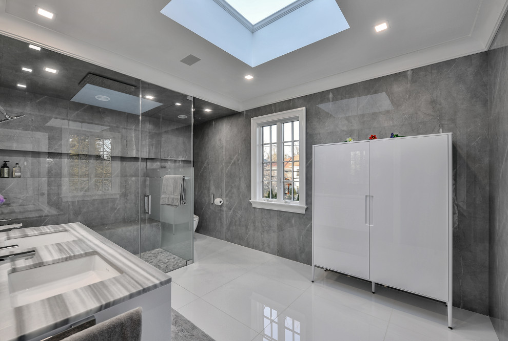 Large modern master bathroom in New York with flat-panel cabinets, white cabinets, a curbless shower, a bidet, gray tile, porcelain tile, grey walls, marble floors, an integrated sink, marble benchtops, white floor, a hinged shower door, grey benchtops, a shower seat, a double vanity, a floating vanity and coffered.