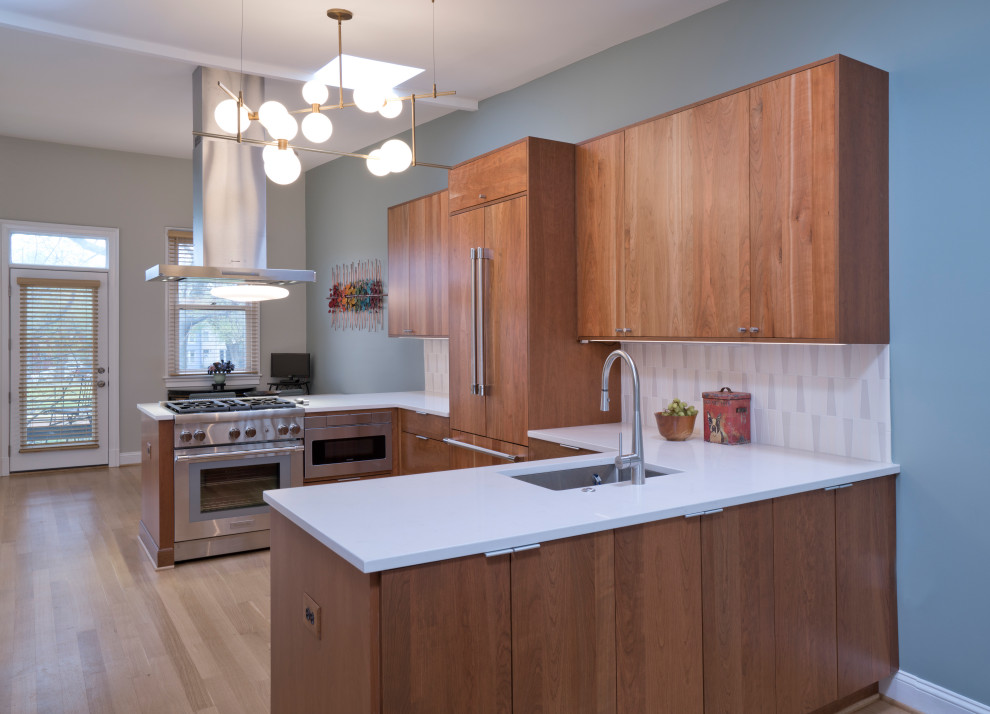 Foto på ett mellanstort retro vit kök, med en undermonterad diskho, släta luckor, skåp i mellenmörkt trä, bänkskiva i kvarts, vitt stänkskydd, stänkskydd i keramik, integrerade vitvaror, ljust trägolv, en halv köksö och beiget golv