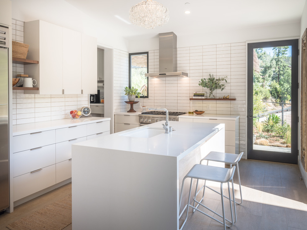 Design ideas for a mid-sized contemporary kitchen in Los Angeles with an undermount sink, flat-panel cabinets, white cabinets, quartz benchtops, white splashback, subway tile splashback, stainless steel appliances, with island and beige floor.