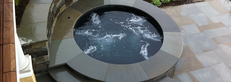 Photo of a mid-sized modern backyard round natural pool in Burlington with a hot tub and natural stone pavers.