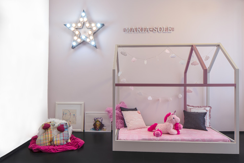 This is an example of a mid-sized modern kids' bedroom for kids 4-10 years old and girls in Rome with pink walls, painted wood floors and black floor.