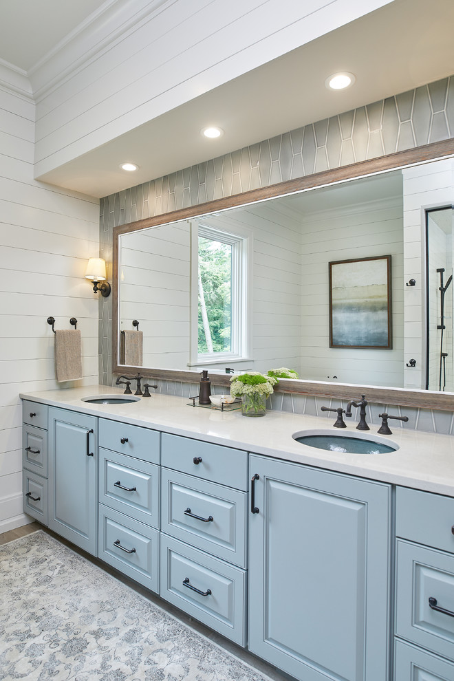 Inspiration for a beach style master bathroom in Grand Rapids with a drop-in tub, white tile, ceramic tile, white walls, an undermount sink and brown floor.