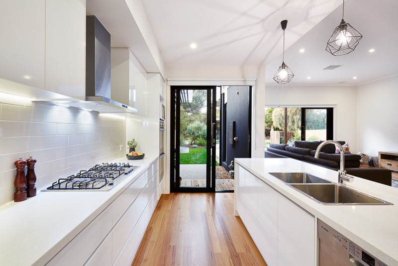 Inspiration for a mid-sized modern single-wall kitchen pantry in Melbourne with a double-bowl sink, raised-panel cabinets, white cabinets, marble benchtops, white splashback, ceramic splashback, stainless steel appliances, light hardwood floors and with island.
