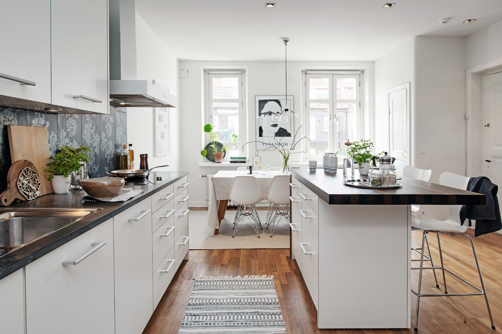 Design ideas for a mid-sized scandinavian single-wall eat-in kitchen in Gothenburg with a single-bowl sink, flat-panel cabinets, white cabinets, concrete benchtops, medium hardwood floors and with island.
