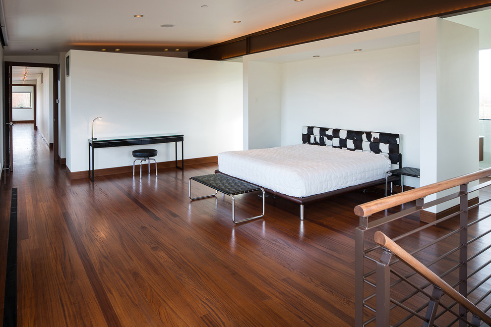 Large contemporary master bedroom in Other with white walls, dark hardwood floors, no fireplace and brown floor.