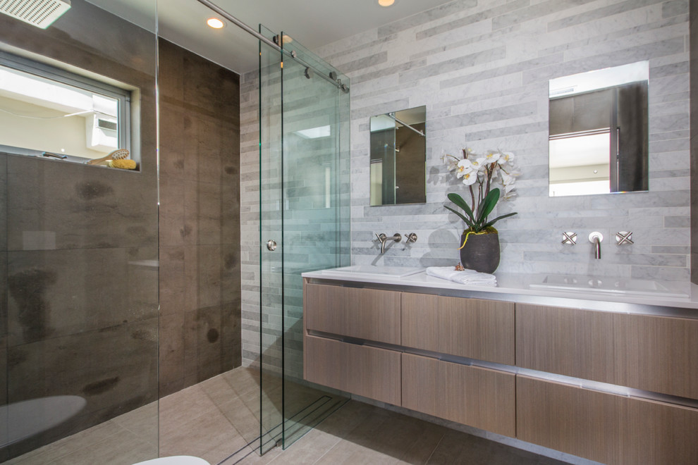 This is an example of a mid-sized contemporary master bathroom in San Diego with a vessel sink, flat-panel cabinets, light wood cabinets, engineered quartz benchtops, a freestanding tub, a curbless shower, white tile, stone tile, white walls and marble floors.