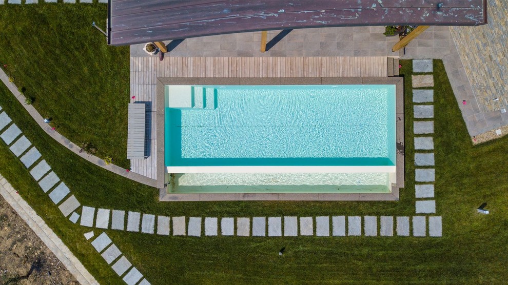 This is an example of a mid-sized modern front yard rectangular infinity pool in Other.