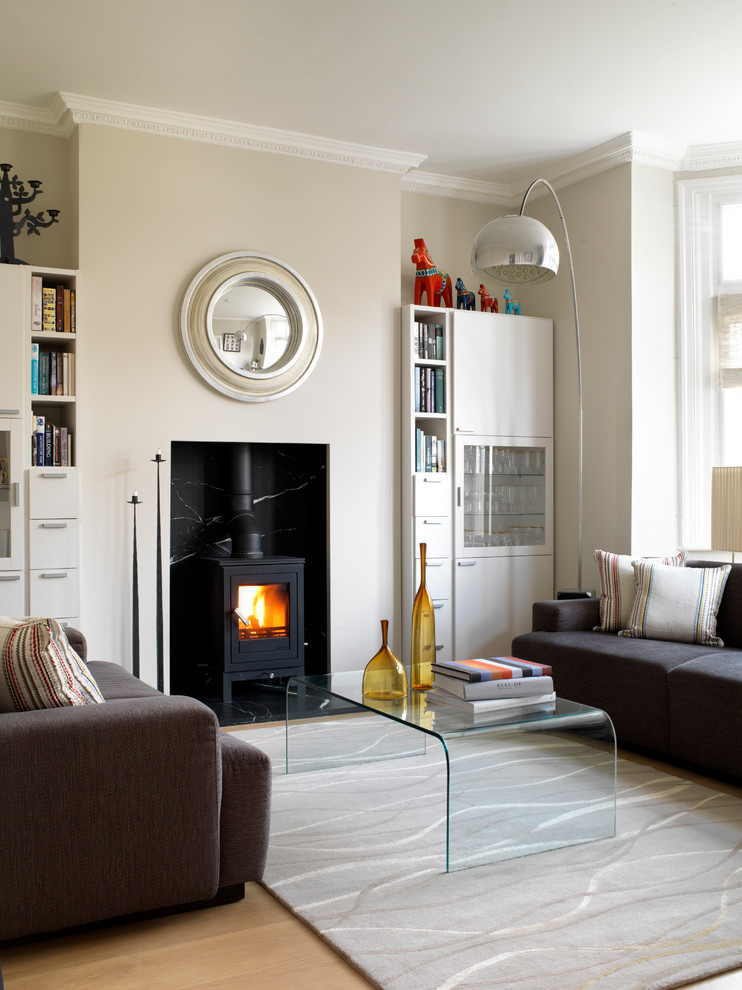 Design ideas for a transitional formal living room in London with beige walls, light hardwood floors and a wood stove.