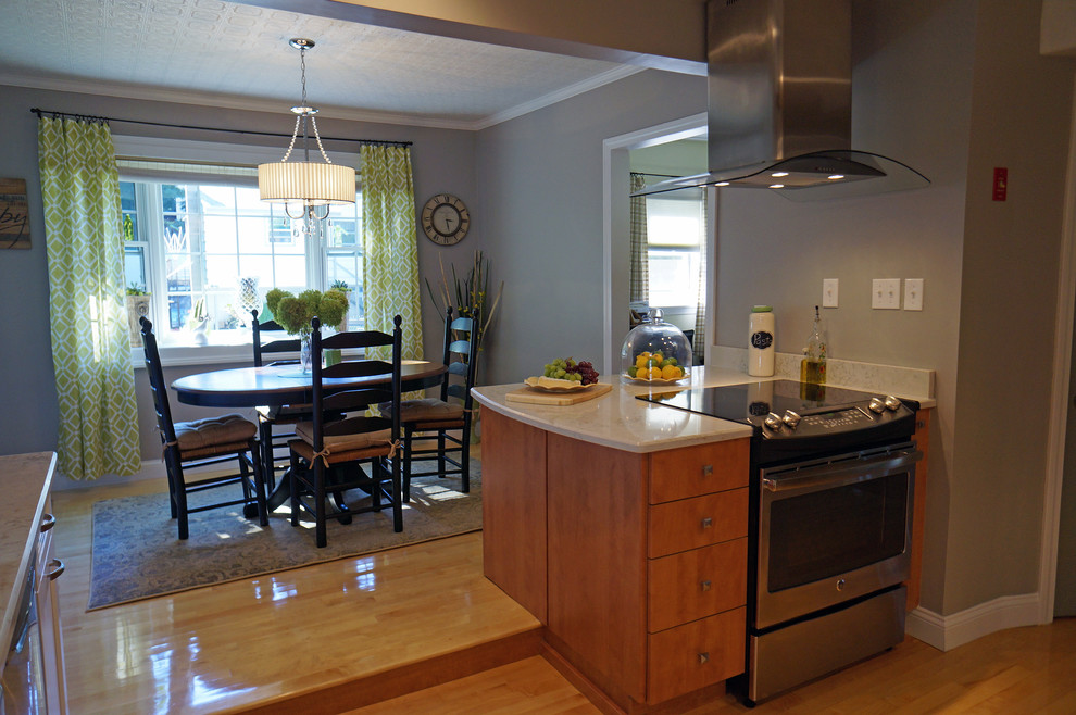 Inspiration for a large transitional l-shaped light wood floor eat-in kitchen remodel in Boston with a farmhouse sink, shaker cabinets, white cabinets, quartz countertops, white backsplash, stone slab backsplash, stainless steel appliances and an island