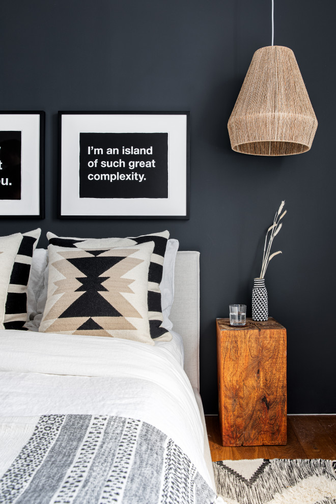 Ejemplo de habitación de invitados ecléctica pequeña con paredes negras y suelo de madera en tonos medios