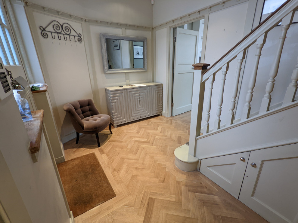 Example of a large minimalist medium tone wood floor hallway design in London