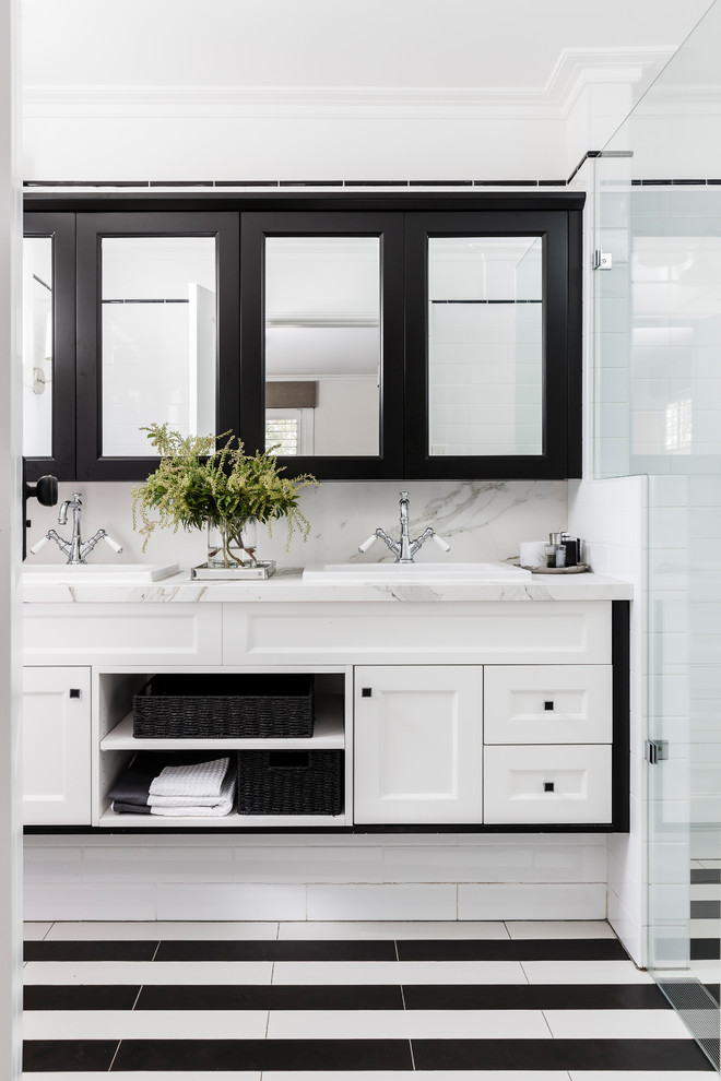 Inspiration for a transitional 3/4 bathroom in Sydney with shaker cabinets, white cabinets, white tile, subway tile, white walls, a drop-in sink, marble benchtops and black floor.