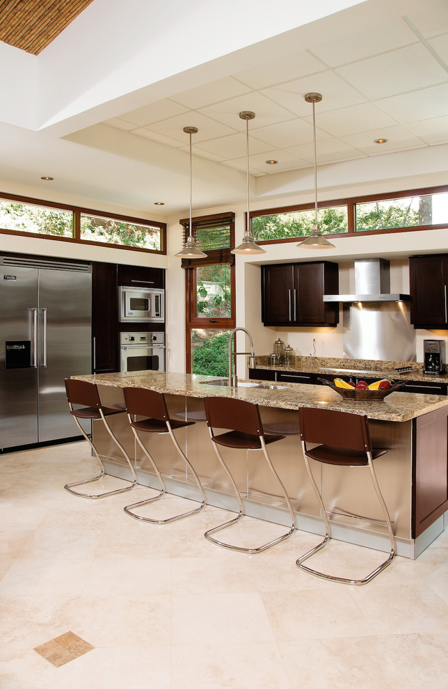 This is an example of a large contemporary u-shaped eat-in kitchen in Other with dark wood cabinets, stainless steel appliances, with island, an undermount sink, flat-panel cabinets, granite benchtops, porcelain floors, beige floor and brown benchtop.