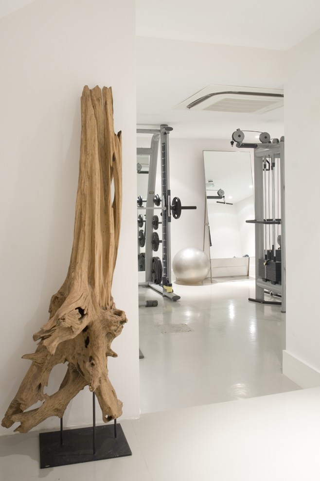 Photo of a contemporary home weight room in London with white walls and white floor.