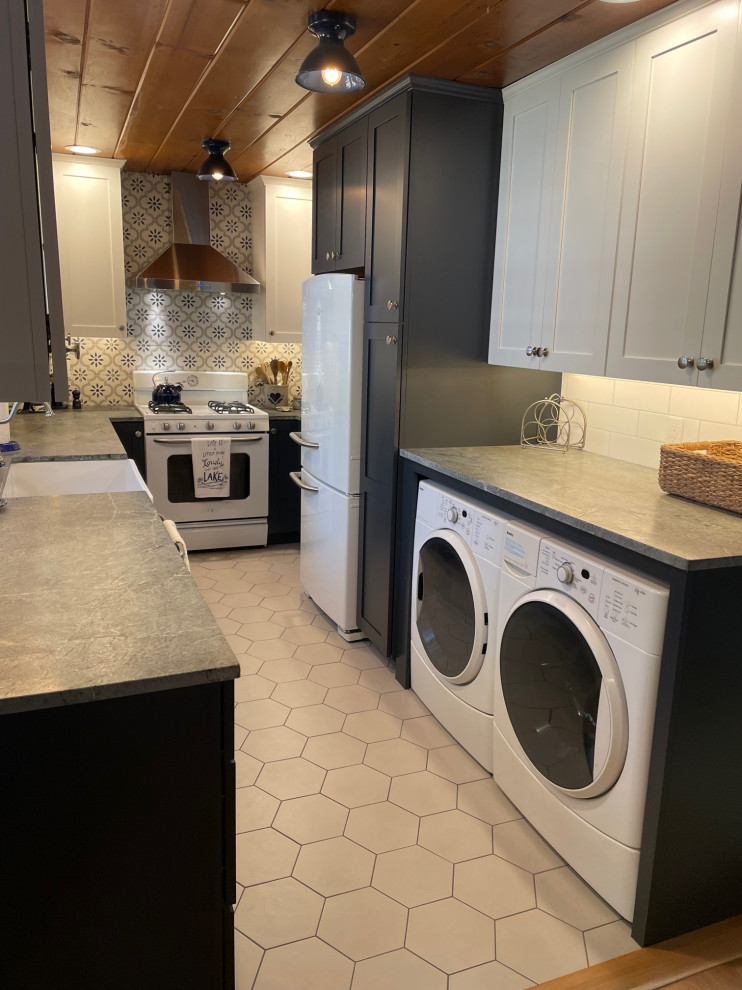 Photo of a small rural kitchen in Other with a belfast sink, shaker cabinets, blue cabinets, soapstone worktops, white splashback, metro tiled splashback, white appliances, porcelain flooring, grey floors and a wood ceiling.