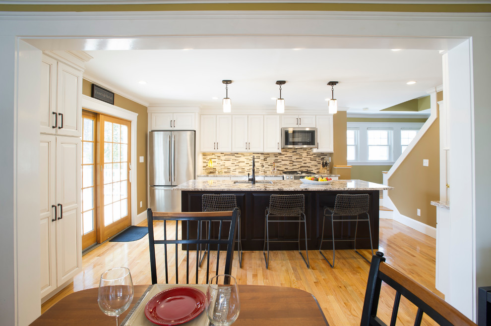 Inspiration for a mid-sized transitional galley light wood floor eat-in kitchen remodel in Boston with an undermount sink, raised-panel cabinets, white cabinets, granite countertops, multicolored backsplash, ceramic backsplash, stainless steel appliances and an island