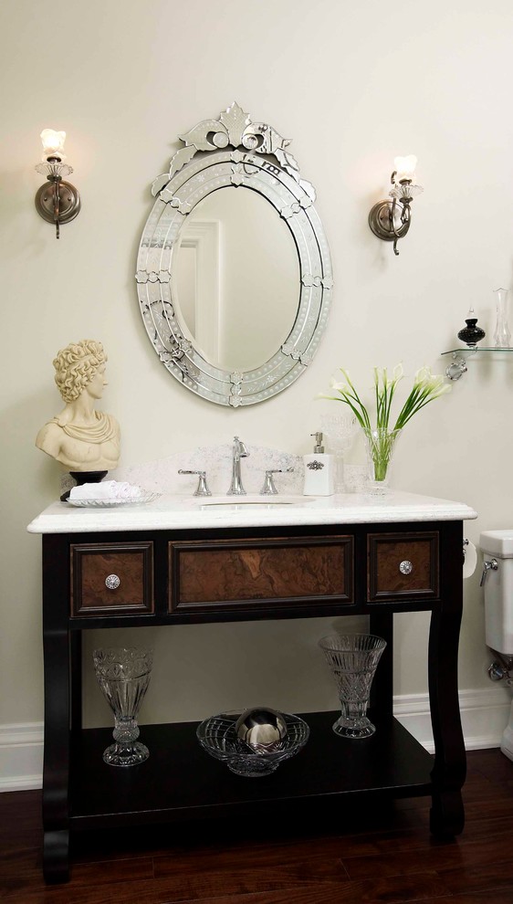 Inspiration for a mid-sized traditional powder room in Toronto with recessed-panel cabinets, dark wood cabinets, a one-piece toilet, white walls, dark hardwood floors, an undermount sink and marble benchtops.