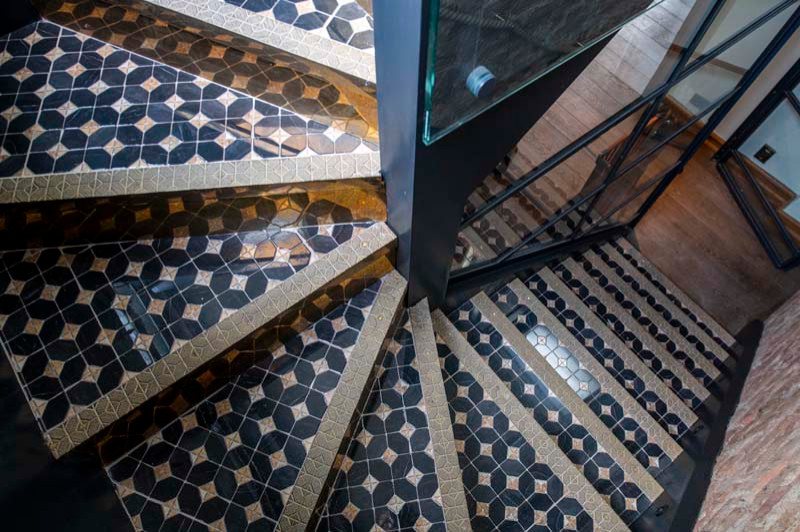 ロンドンにある高級な広いコンテンポラリースタイルのおしゃれな折り返し階段 (金属の蹴込み板、ワイヤーの手すり、レンガ壁) の写真