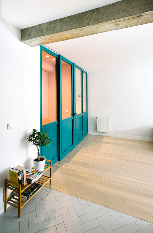 This is an example of a small contemporary hallway in Madrid with white walls and light hardwood floors.