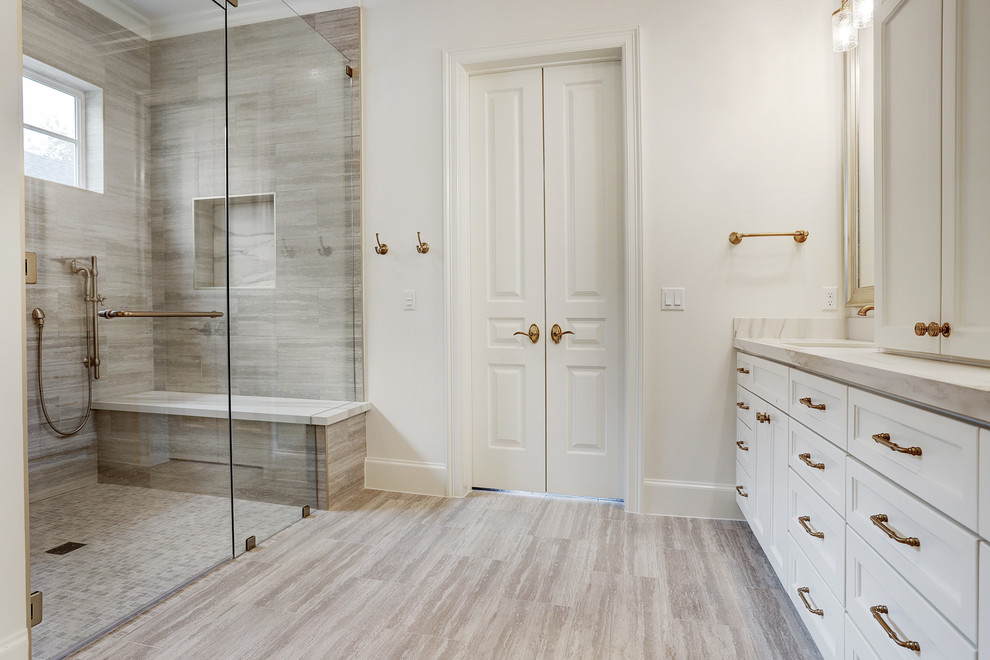 Photo of a transitional master bathroom in Houston with recessed-panel cabinets, white cabinets, beige tile, limestone, white walls, limestone floors, an undermount sink, quartzite benchtops, beige floor, a hinged shower door and white benchtops.