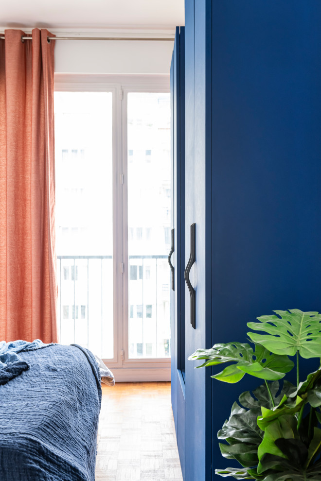 Cette photo montre une chambre parentale tendance de taille moyenne avec un mur bleu, parquet clair, aucune cheminée, un sol beige et dressing.