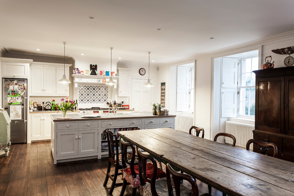 Traditional galley eat-in kitchen in Edinburgh with medium hardwood floors, with island, shaker cabinets, white cabinets, multi-coloured splashback, mosaic tile splashback and stainless steel appliances.