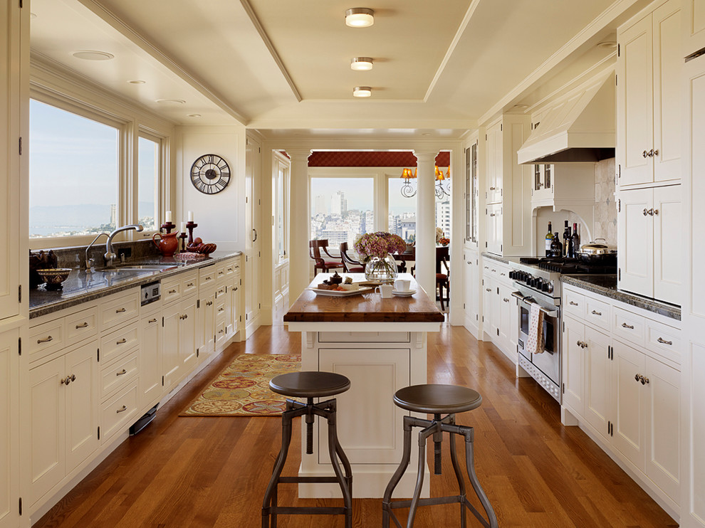 Design ideas for a large traditional galley separate kitchen in San Francisco with an undermount sink, shaker cabinets, white cabinets, white splashback, ceramic splashback, stainless steel appliances, medium hardwood floors and with island.