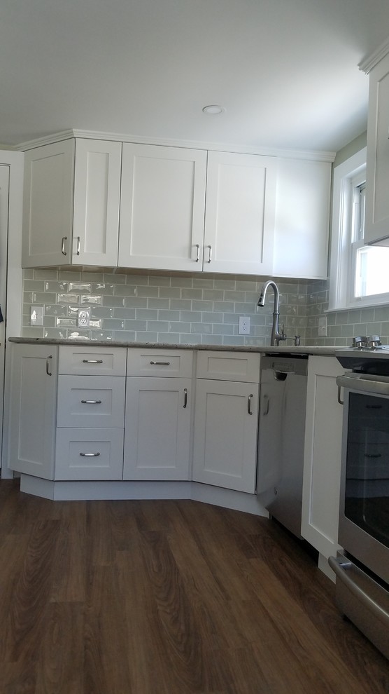 Photo of a small traditional l-shaped separate kitchen in Boston with an undermount sink, shaker cabinets, white cabinets, granite benchtops, green splashback, subway tile splashback, stainless steel appliances, vinyl floors, no island, brown floor and grey benchtop.