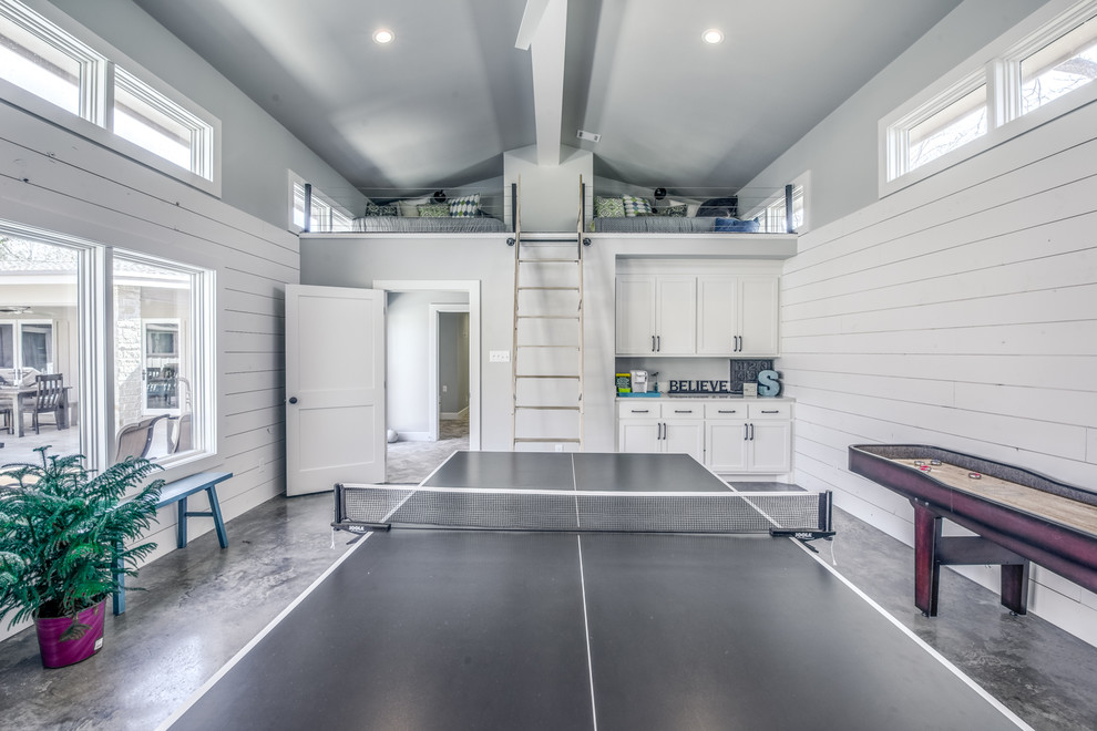 This is an example of a large country open concept family room in Austin with a game room, white walls, concrete floors and a wall-mounted tv.