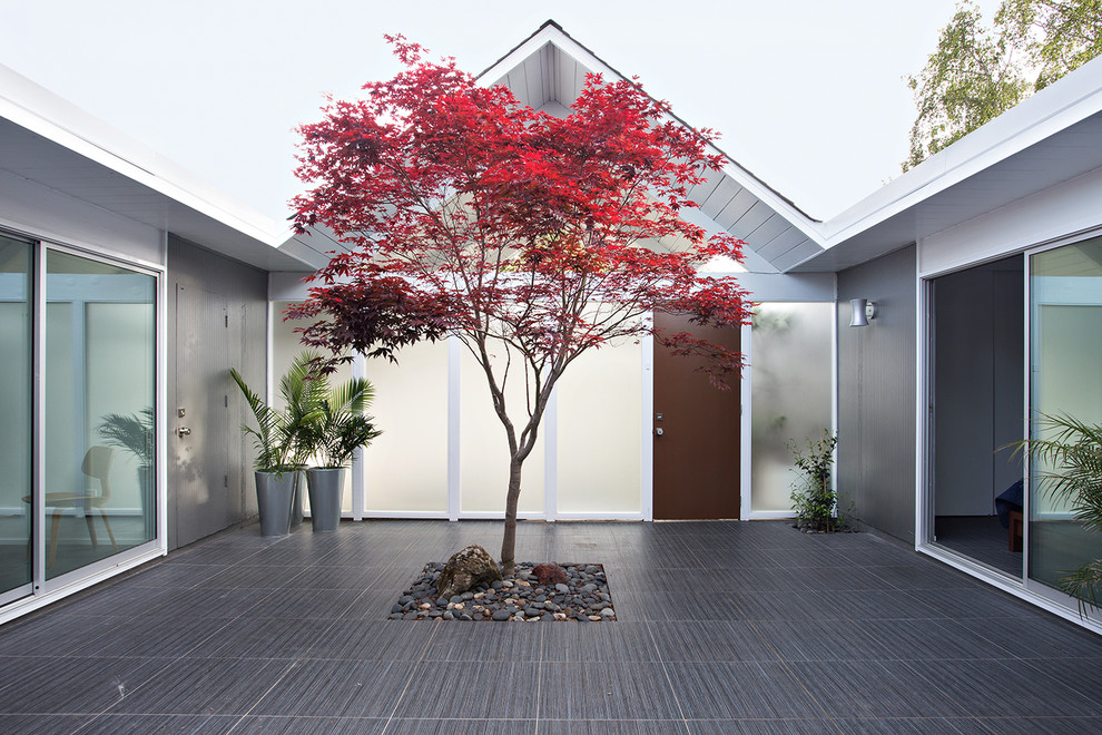 This is an example of a midcentury courtyard patio in San Francisco with tile and no cover.