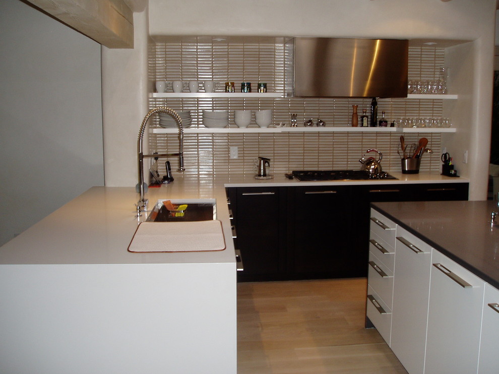 Photo of a mid-sized contemporary l-shaped separate kitchen in Albuquerque with an undermount sink, flat-panel cabinets, white cabinets, quartz benchtops, beige splashback, ceramic splashback, stainless steel appliances, light hardwood floors and with island.